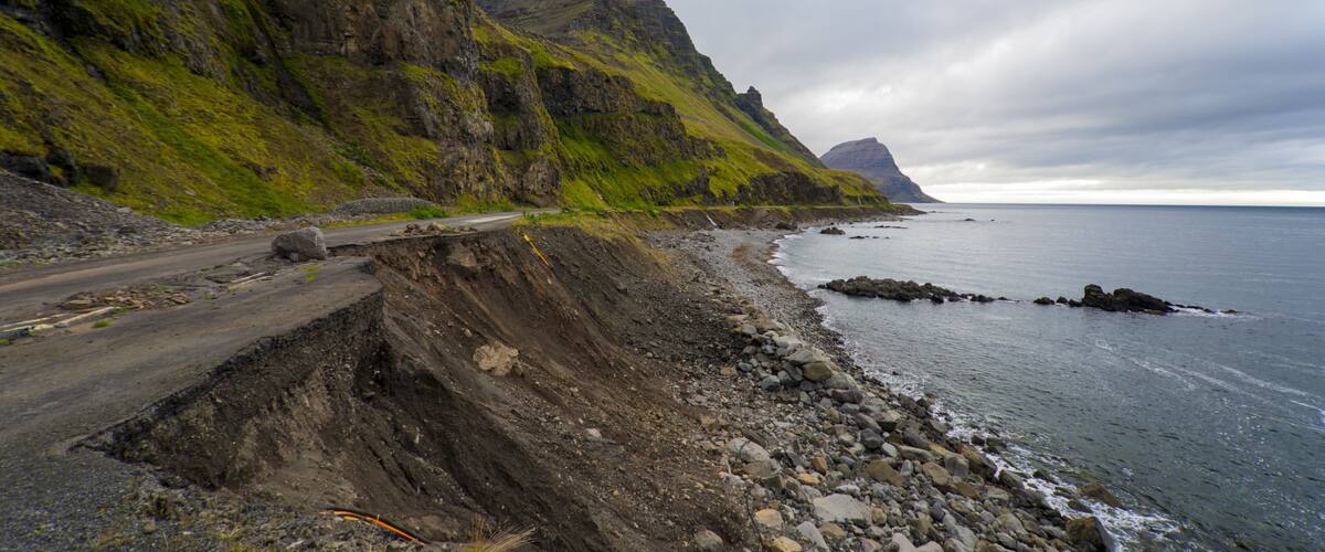 A coastal road with steep cliffs and a rocky shoreline.