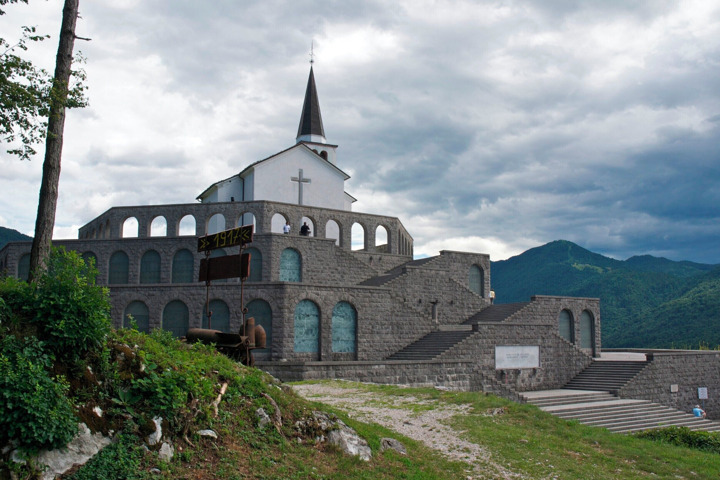A stone church with a cross on the steeple, surrounded by mountains.
