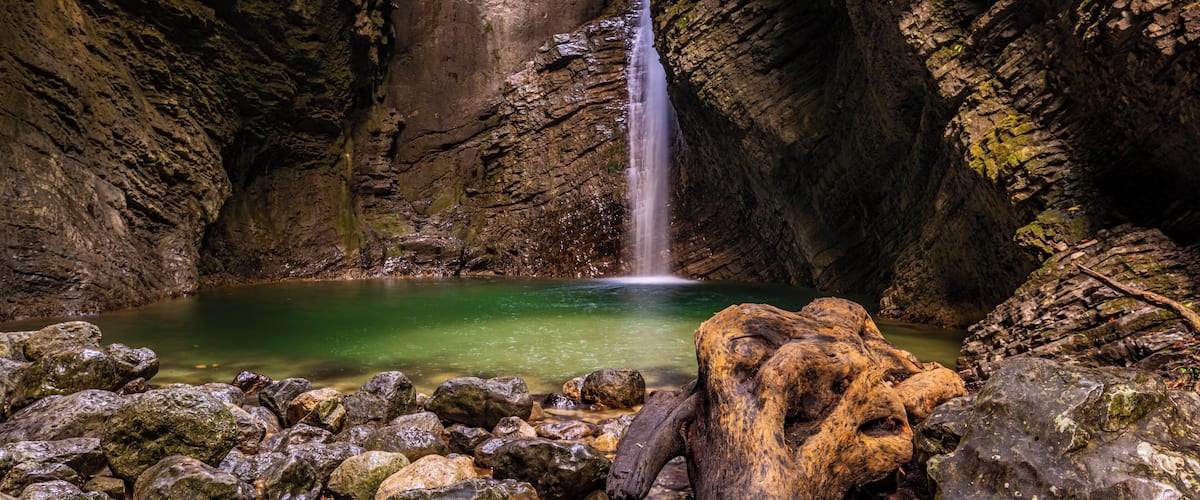 A waterfall in a rocky gorge with a clear pool at the base.