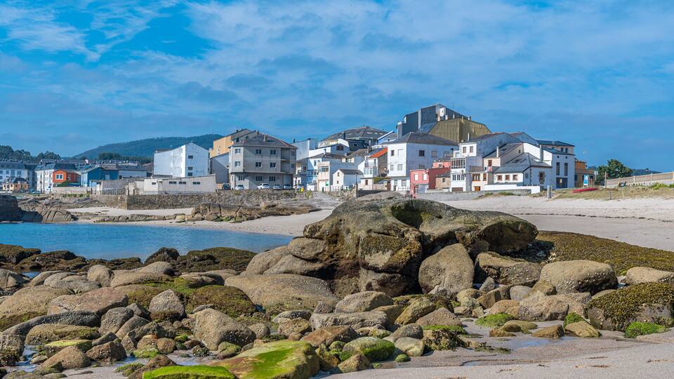 A coastal town with colorful buildings, rocky shoreline, and a clear blue sky.