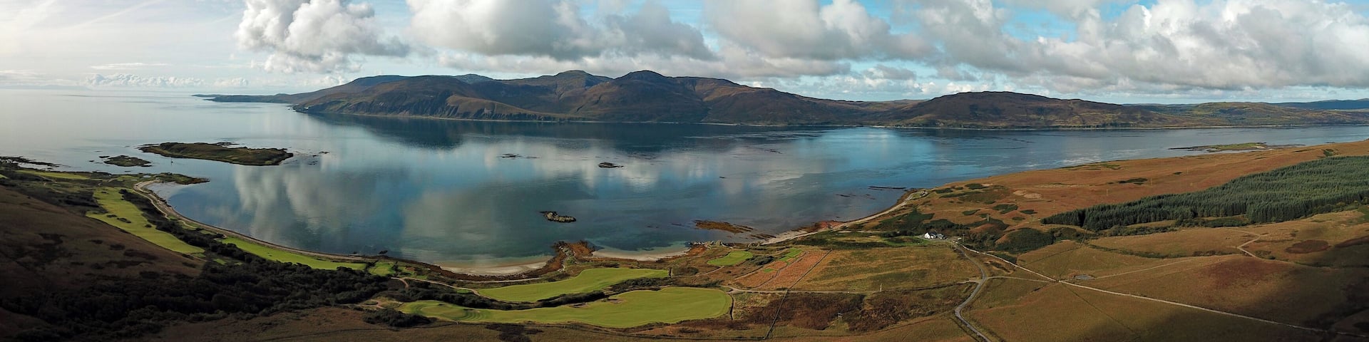 A lake surrounded by mountains and a golf course.