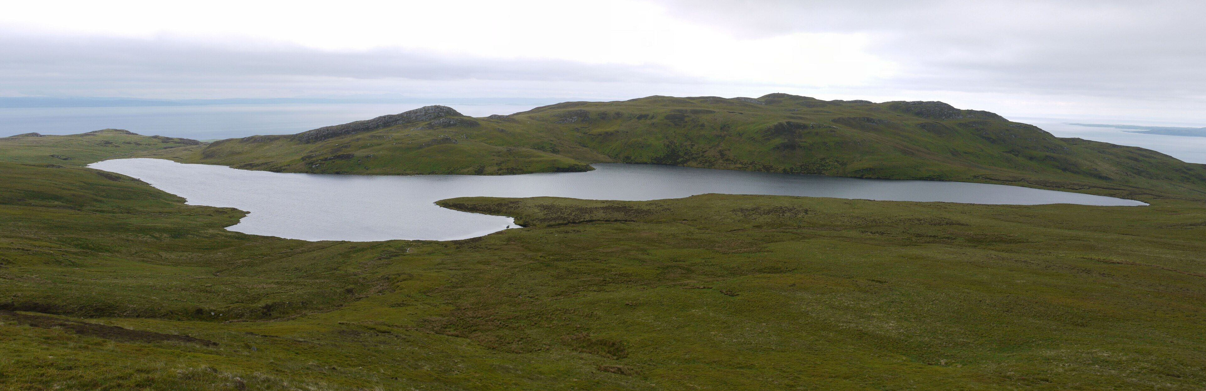 A lake surrounded by green hills and mountains.