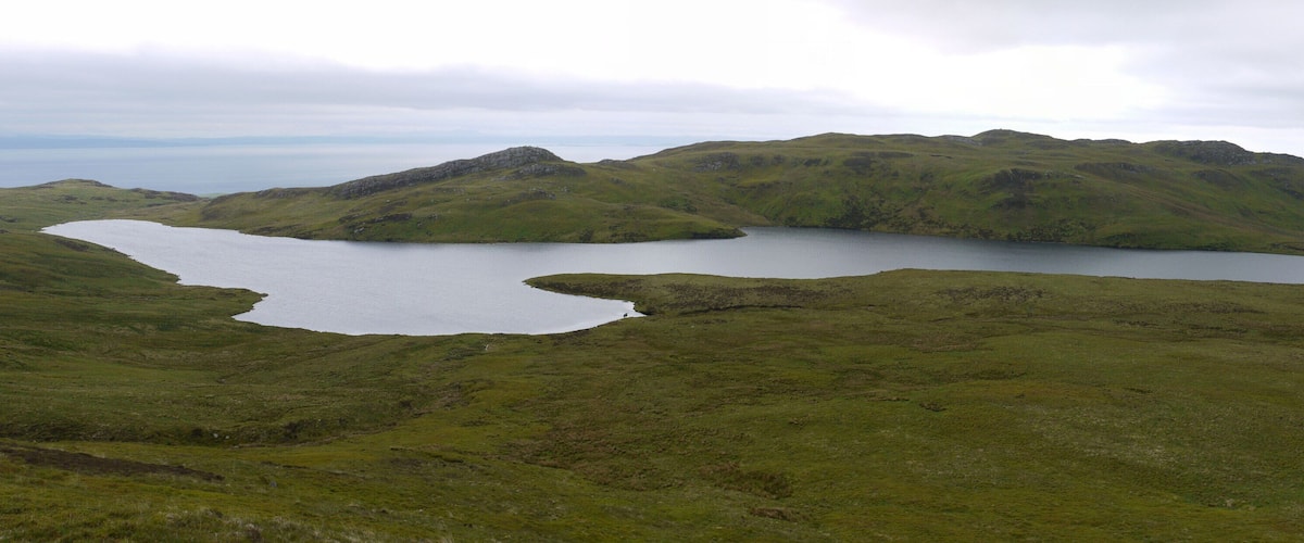 A lake surrounded by green hills and mountains.