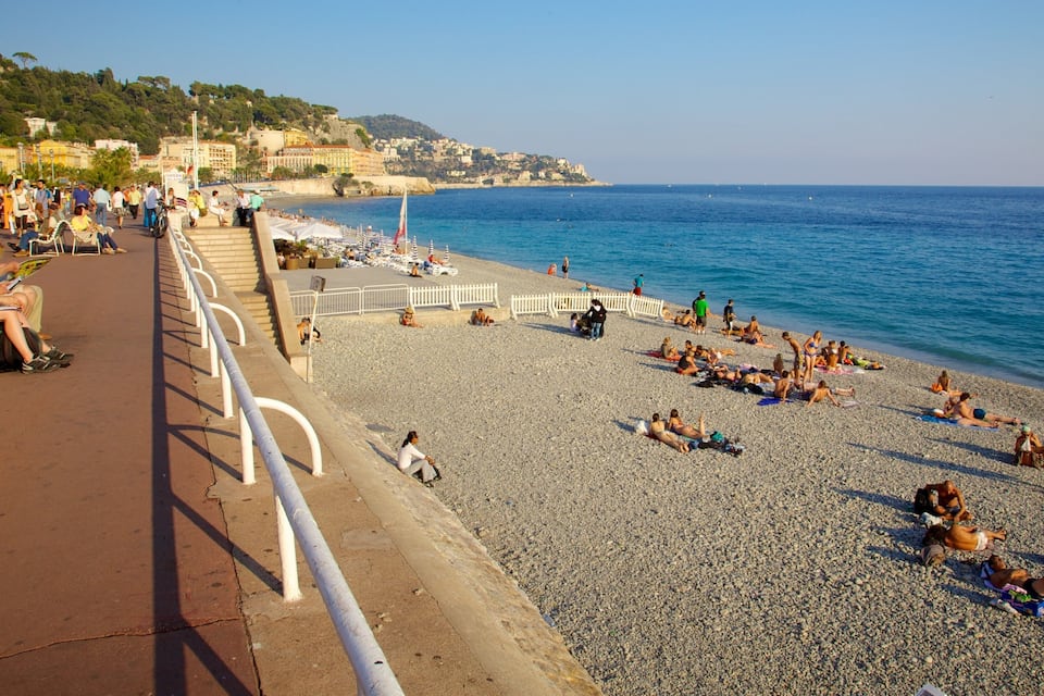 A pebble beach with people sunbathing and walking along the shore.