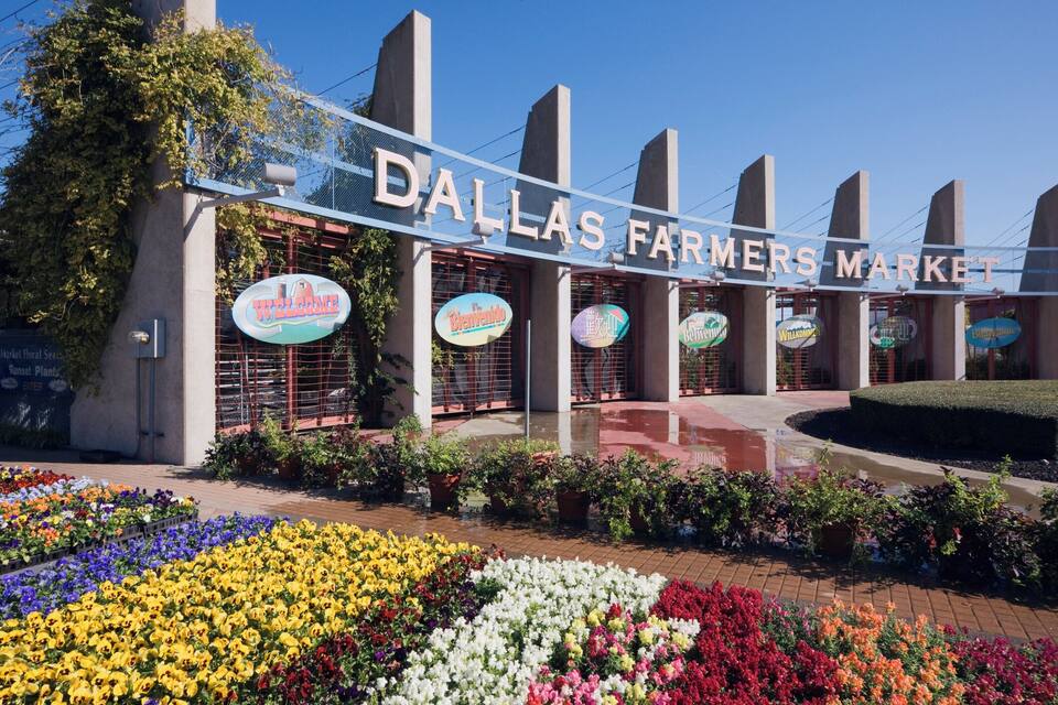 The Dallas Farmers Market entrance with colorful flower beds in front.