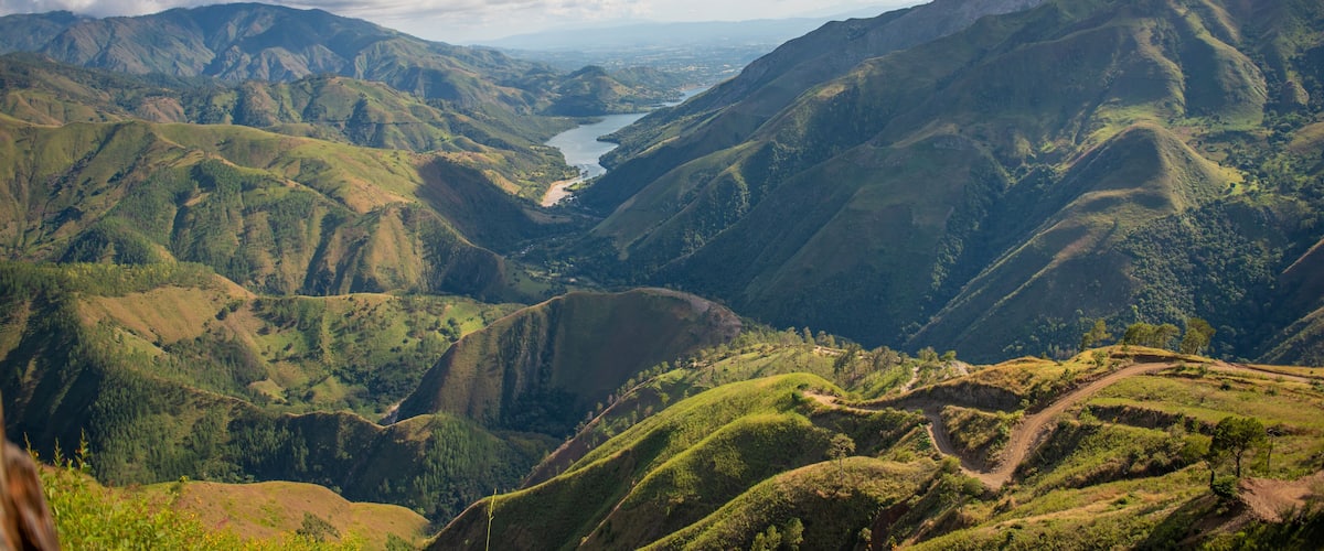 A valley with a river, surrounded by green hills and mountains.