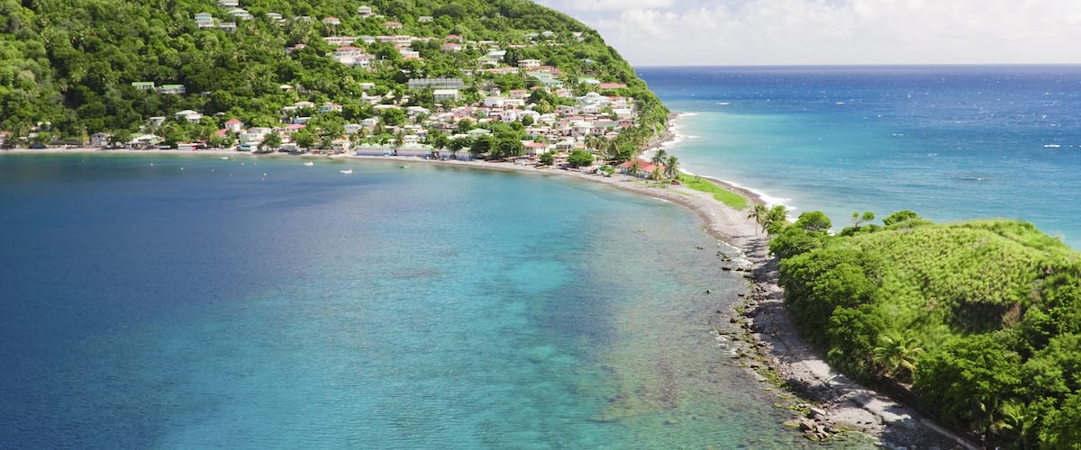 A coastal town with a clear blue sea, a green hillside, and a beach.