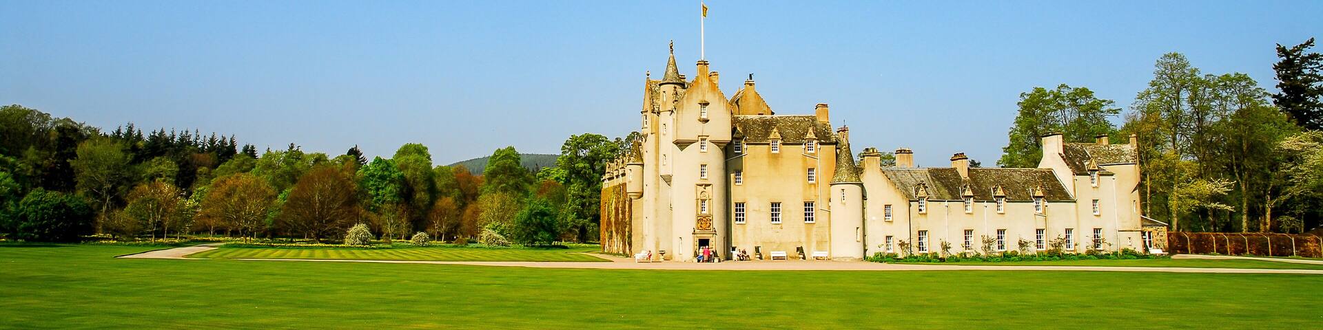 A large castle with a green lawn in front.