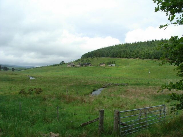 Paisaje rural con un campo cubierto de hierba, un pequeño arroyo y una valla de madera.