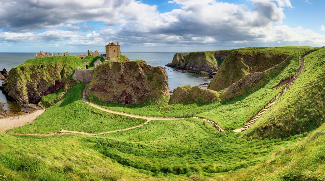 Cliff in a bay with blue sky and white cloudsnear in Dunnottar Castle, Scotland - UK