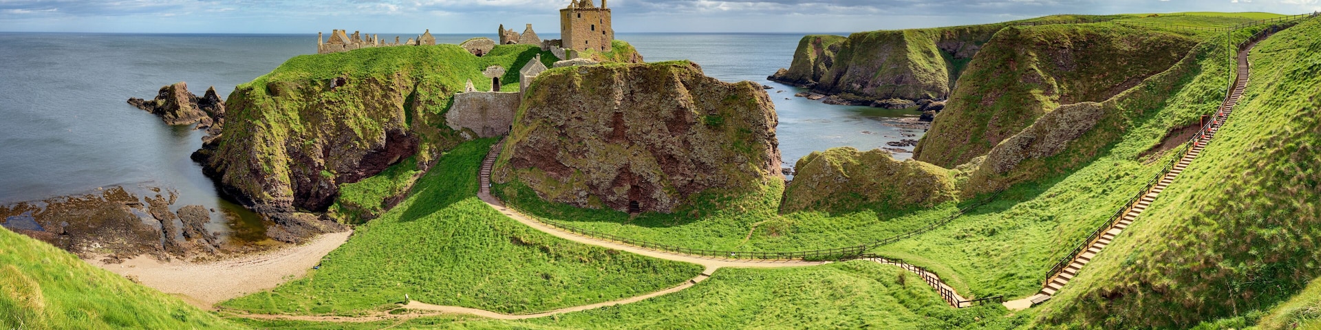 Cliff in a bay with blue sky and white cloudsnear in Dunnottar Castle, Scotland - UK