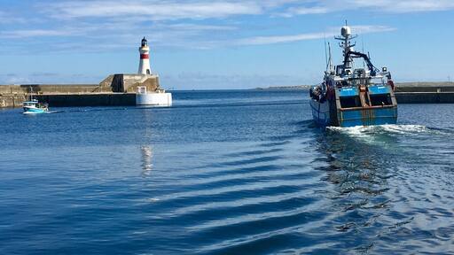 Fishing boats coming and going at Fraserburgh Harbour Scotland