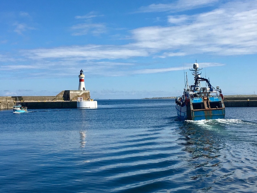 Fishing boats coming and going at Fraserburgh Harbour Scotland