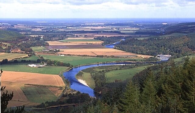 A river winding through a valley with fields and forests.