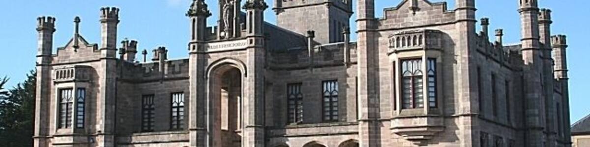 Ein großes, historisches Steingebäude mit mehreren Türmen und Bogenfenstern.
