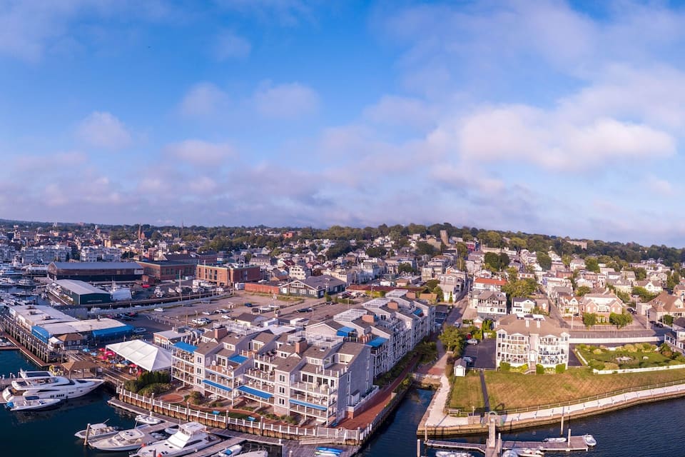 A coastal town with a marina, residential buildings, and a hill in the background.