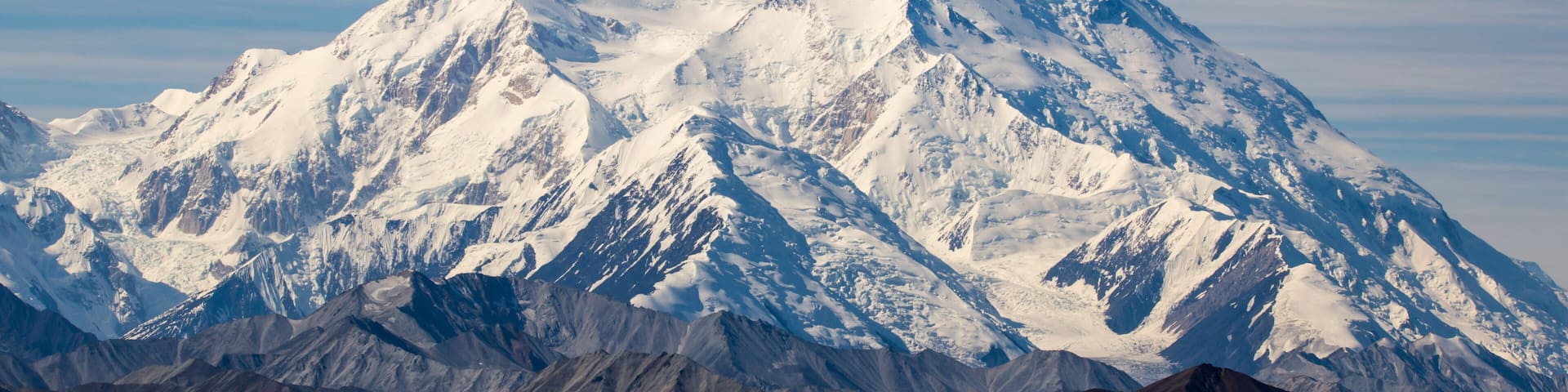 A snow-covered mountain range with rugged terrain and clear skies.