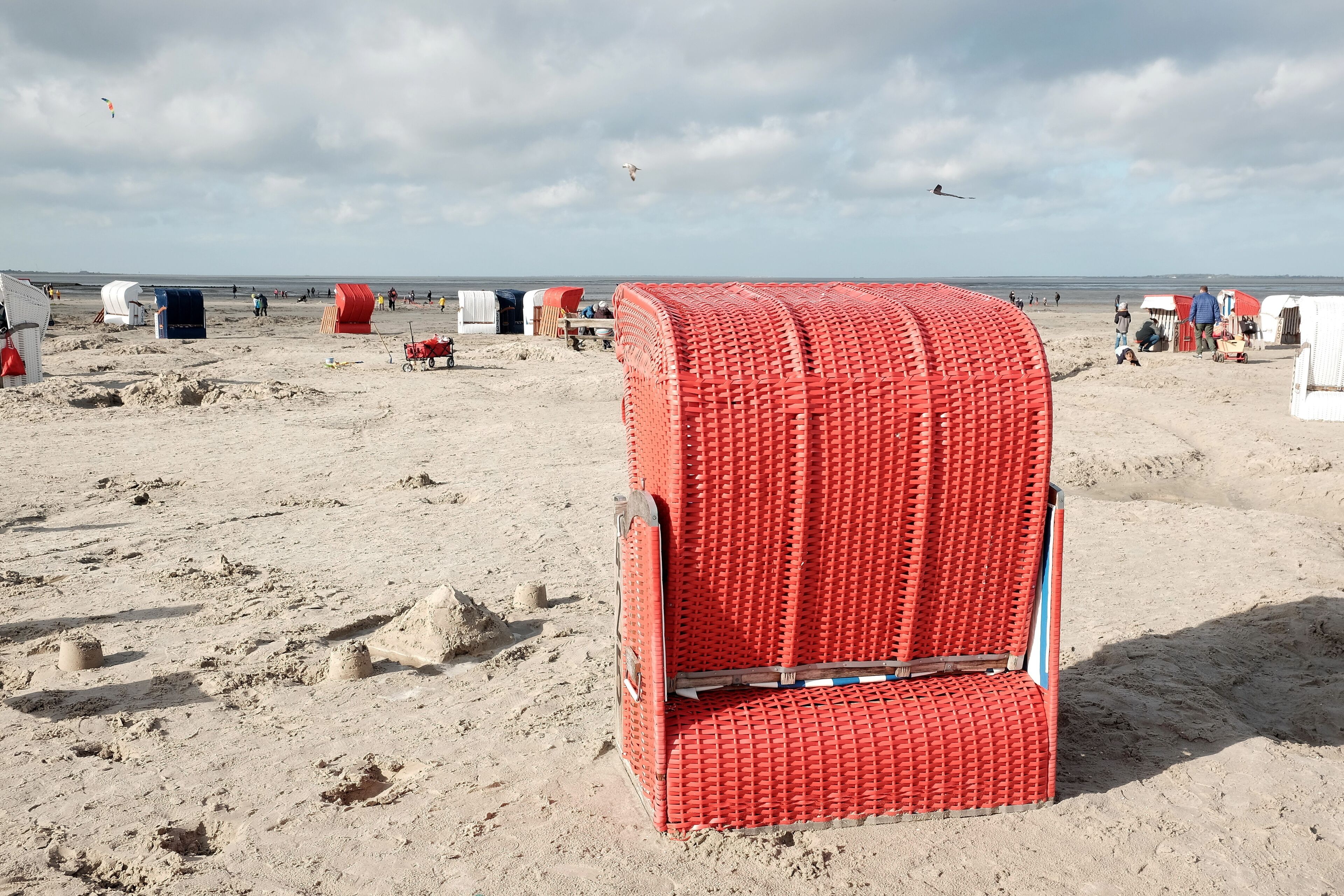 Roter Strandkorb am Strand von Bensersiel im Herbst bei Sonnenschein an der Küste der Nordsee bei Esens in Ostfriesland in Niedersachsen