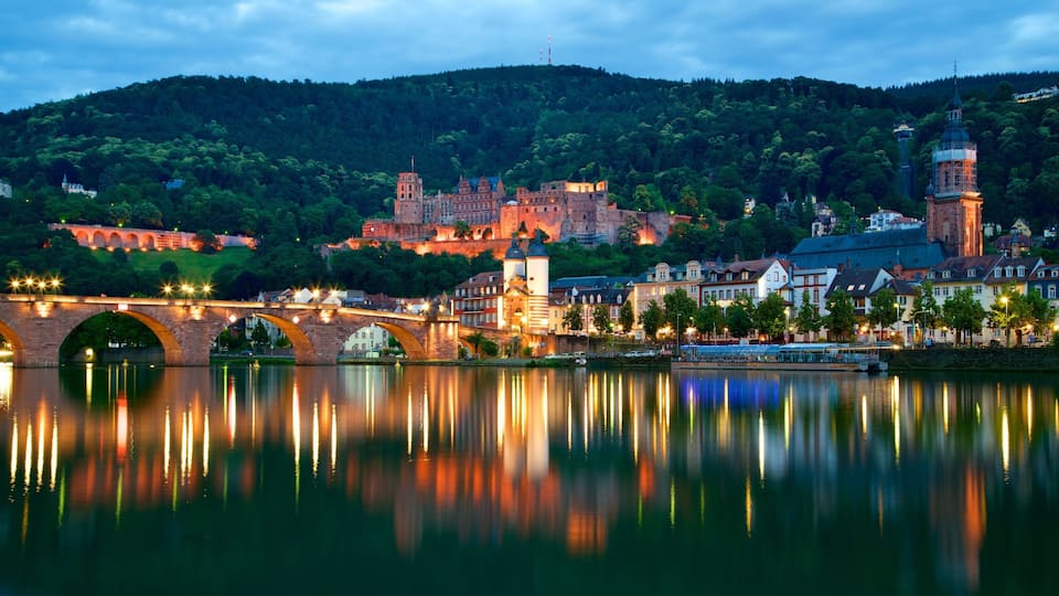 A river with a bridge, a castle, and a church on a hill.
