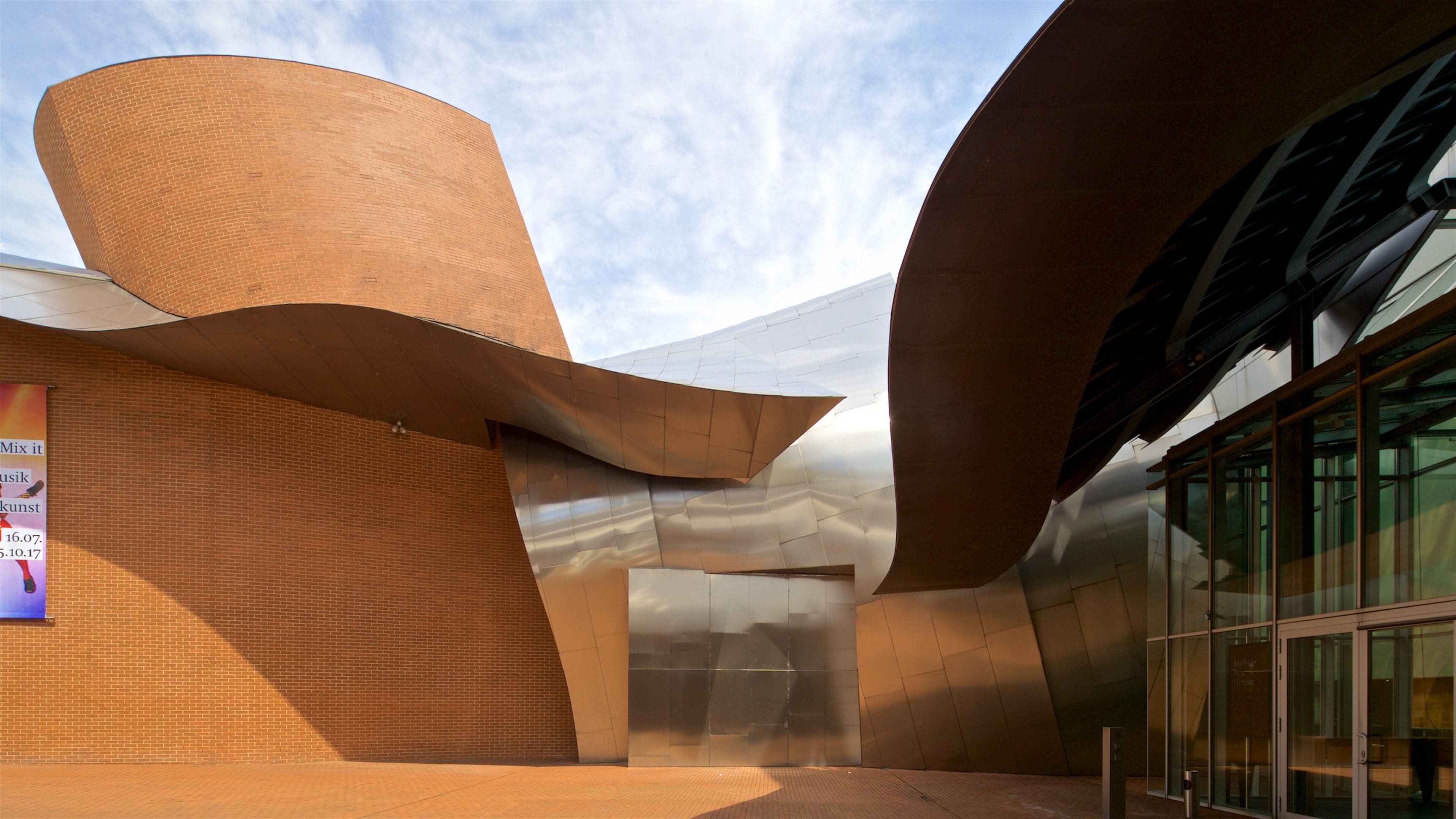 A modern architectural building with curved metal and brick structures.
