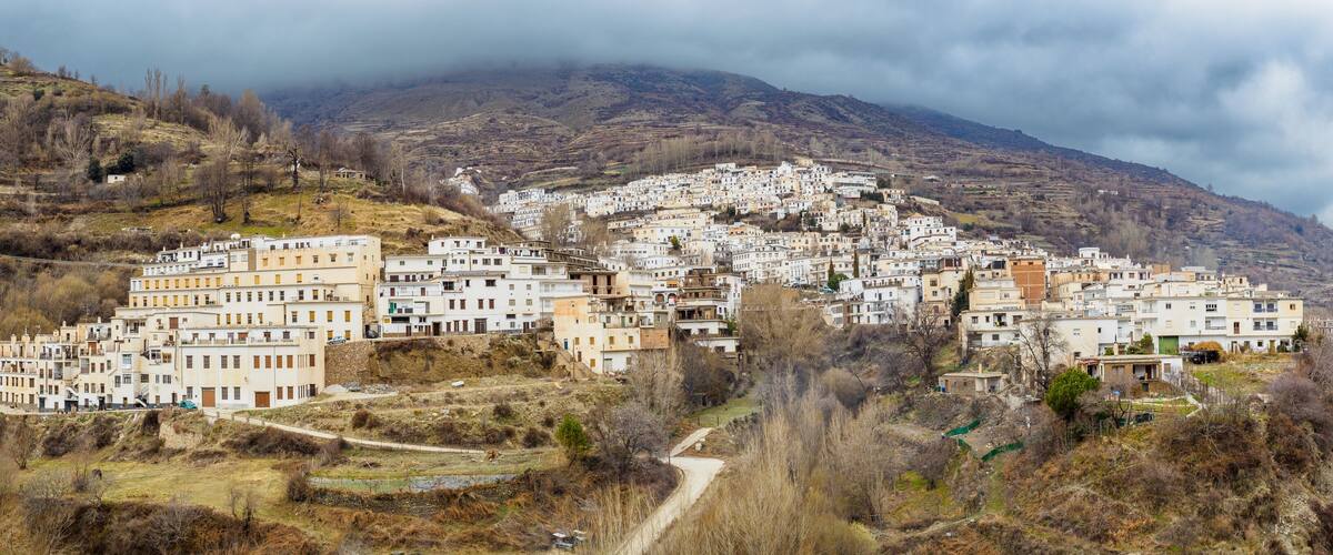 A mountainous village with white buildings nestled in a valley.