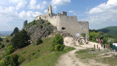 A historic stone castle on a hill with a clear sky.