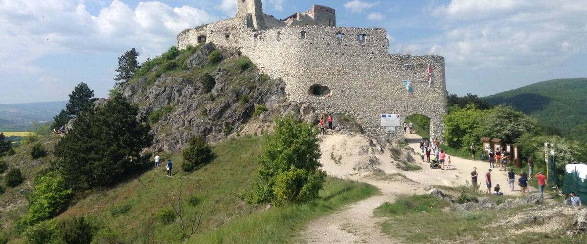 A historic stone castle on a hill with a clear sky.