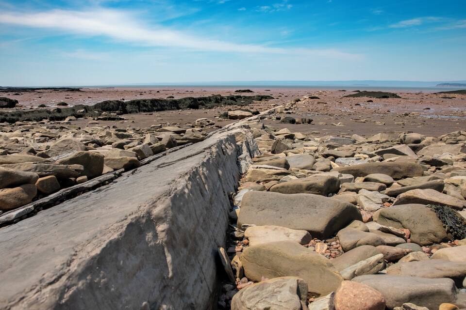 A rocky shoreline with large boulders and a concrete barrier.