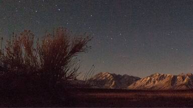 A starry night sky over a mountainous landscape.