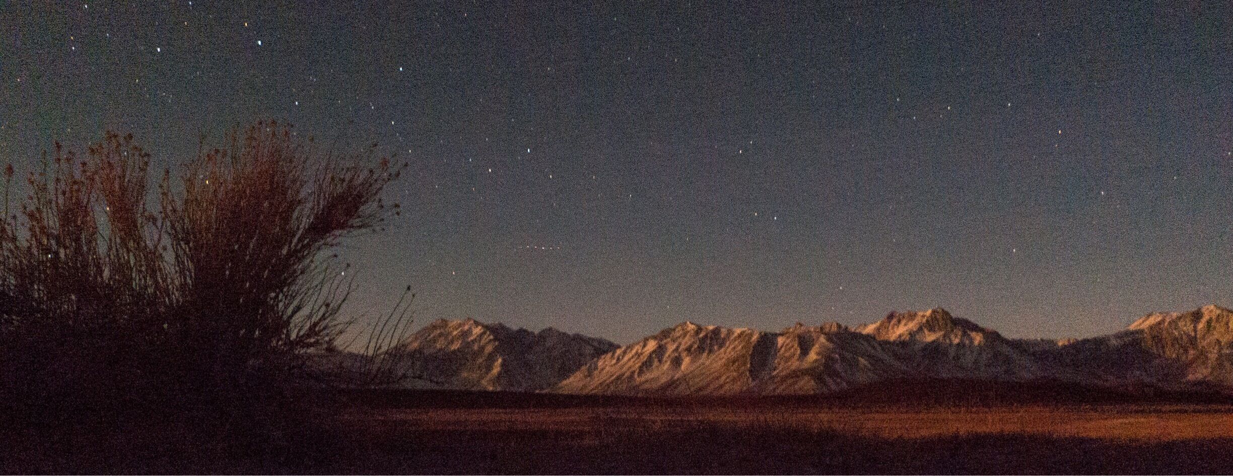 A starry night sky over a mountainous landscape.