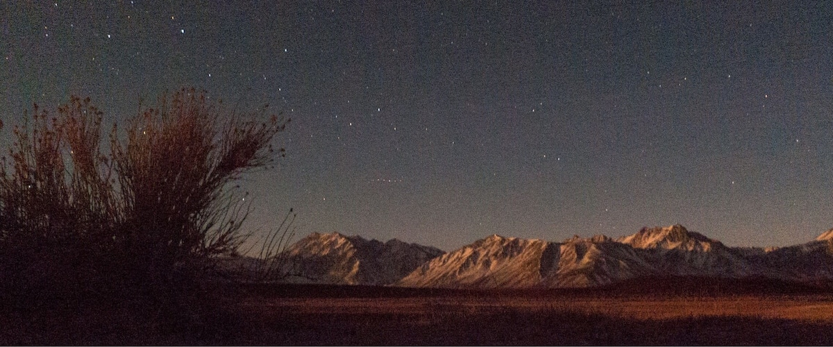 A starry night sky over a mountainous landscape.