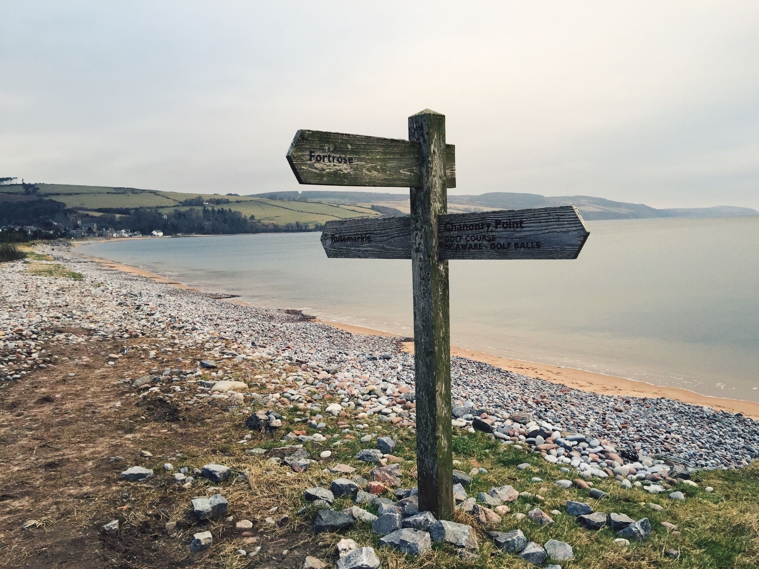 A wooden signpost with directional arrows pointing to 'Fortrose' and 'Rosemarke'.
