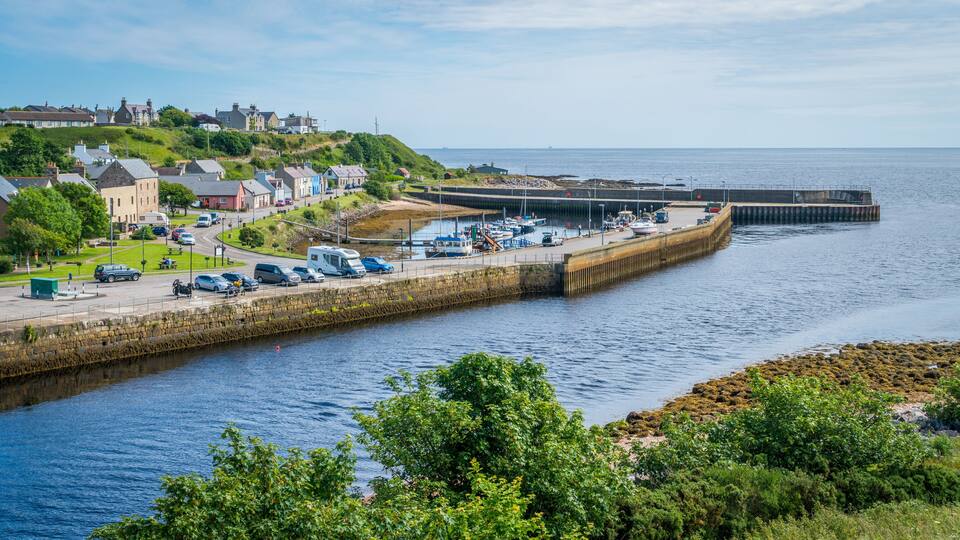 A coastal town with a harbor, boats, and a stone pier.
