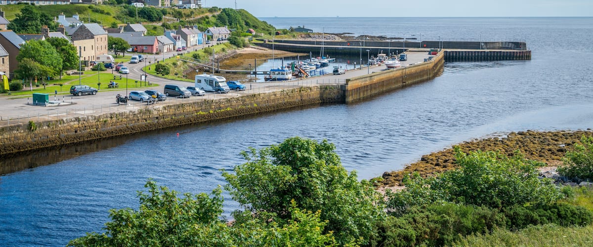 A coastal town with a harbor, boats, and a stone pier.