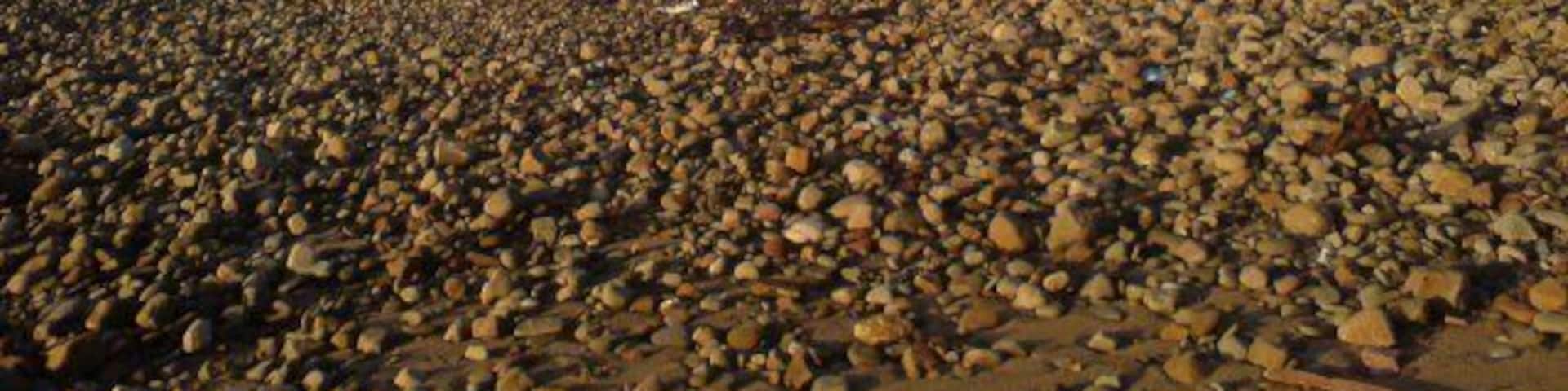 Shore at Kenfig nature Reserve Kenfig Nature Reserve is a large area of sand dunes and buroughs. The three dark structures visible in the distance are cranes, part of Margam steel works. On the map, this area is described as Kenfig Sands - those are pretty big sand grains though...