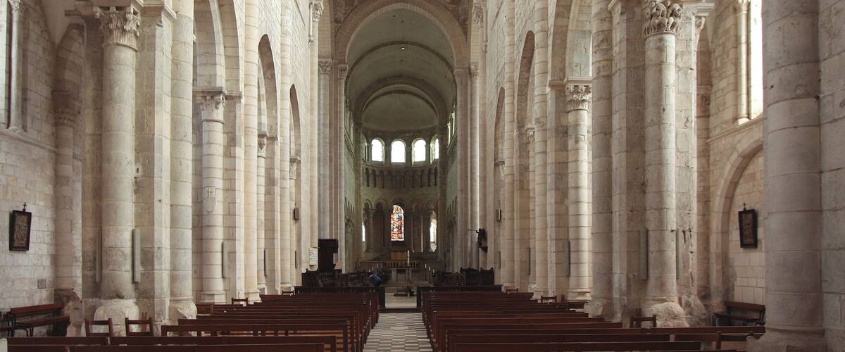 A cathedral interior with high vaulted ceilings, arched columns, and rows of pews.
