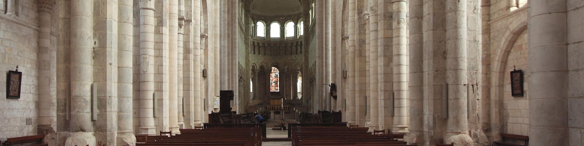 A cathedral interior with high vaulted ceilings, arched columns, and rows of pews.