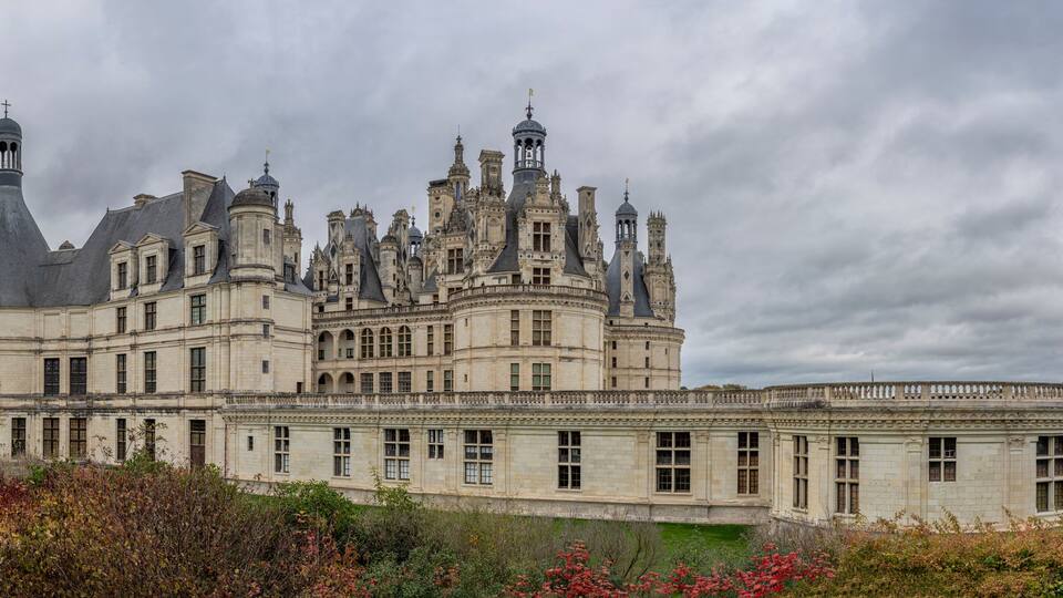 A large, ornate castle with multiple towers and a well-maintained garden.