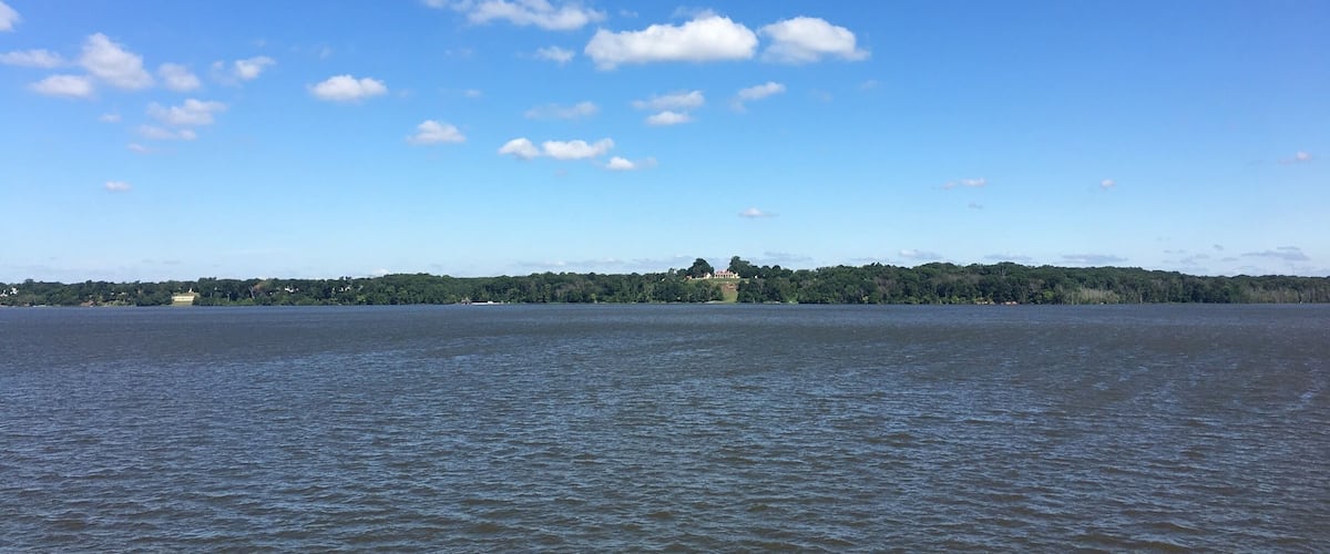 A calm lake with a clear blue sky and scattered clouds.