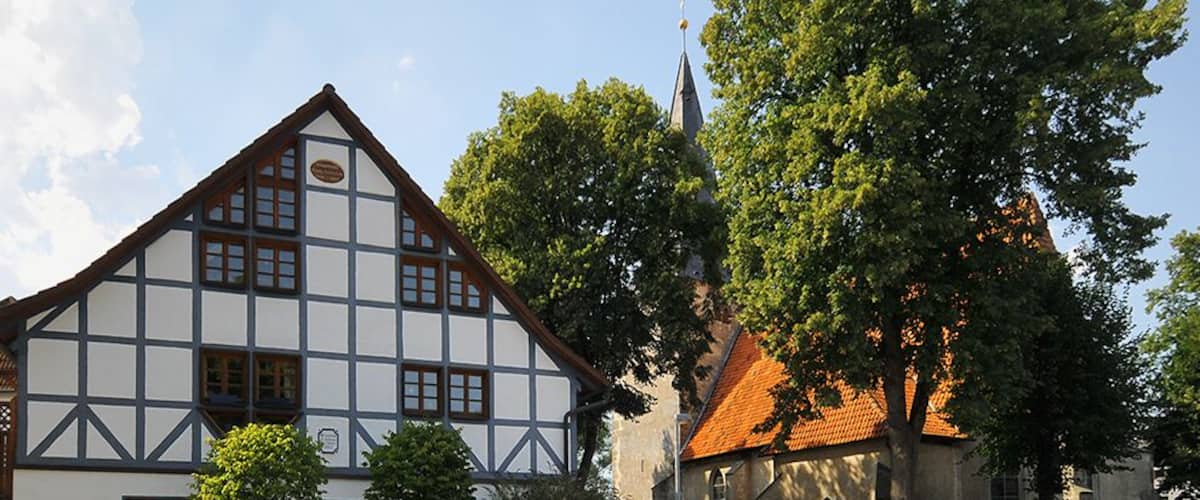 Une maison traditionnelle à colombages, avec une église en arrière-plan.