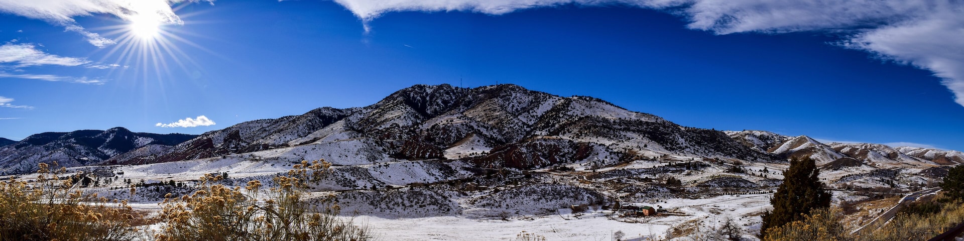 Una cordillera nevada con un cielo azul despejado y el sol brillando.