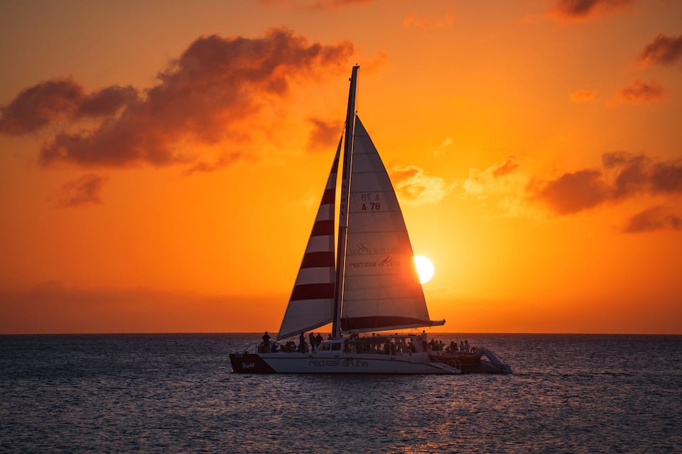 A sailboat with the registration number A 78 sailing on the ocean during sunset.
