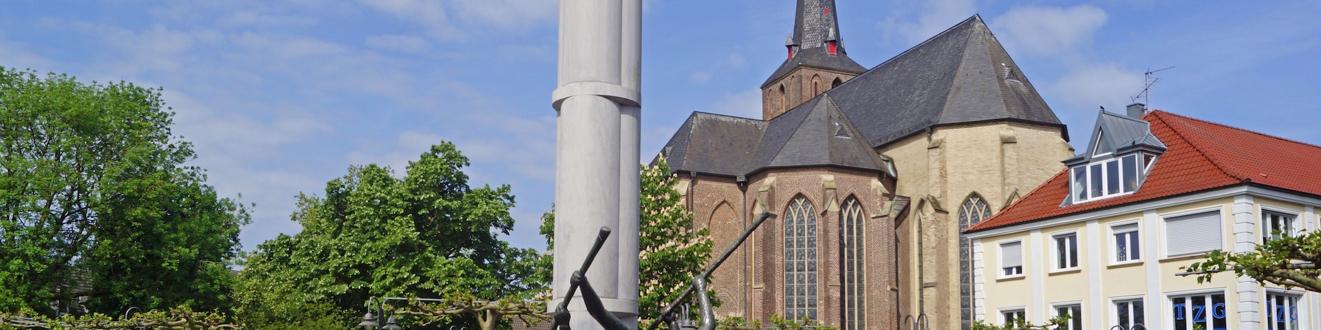 A statue of a bear on a column, a church with a spire, and a building with a red roof.