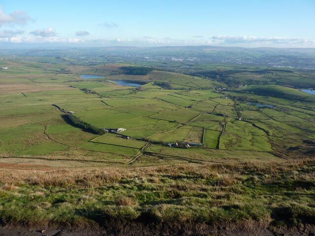 A rural landscape with fields, a small body of water, and scattered buildings.