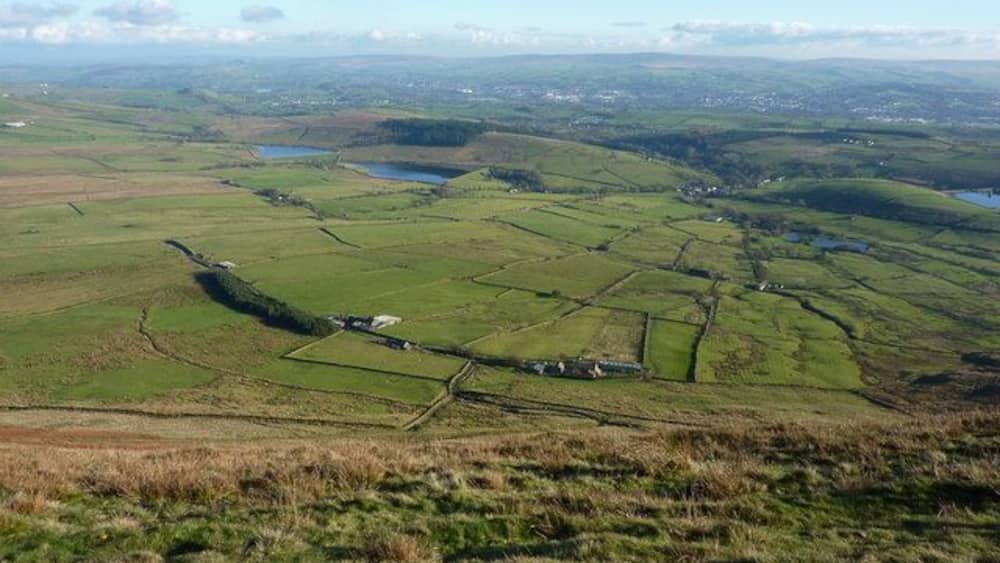 A rural landscape with fields, a small body of water, and scattered buildings.