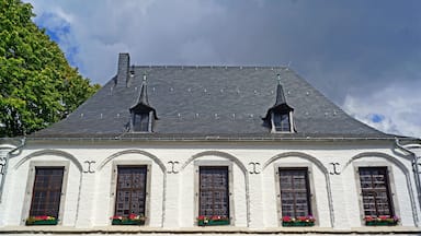Ein weißes Gebäude mit Rundbogenfenstern und einem steilen Walmdach.