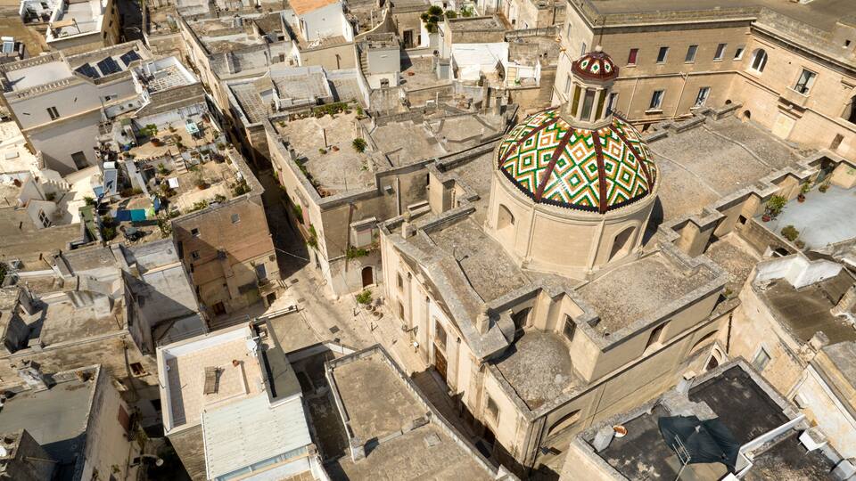 An aerial view of a historic city with a prominent domed building featuring intricate mosaic patterns.