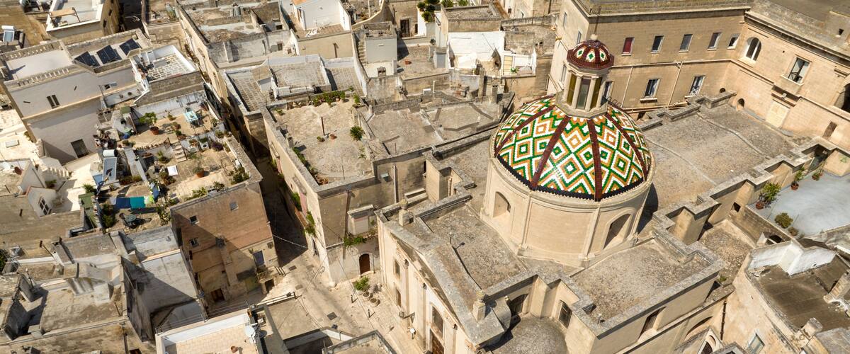 An aerial view of a historic city with a prominent domed building featuring intricate mosaic patterns.