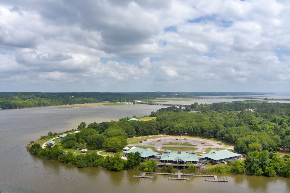 A lakeside resort with a dock, green-roofed buildings, and a parking area.