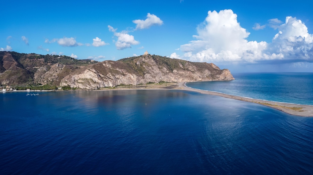 Aerial drone view of Laghetti di Marinello, natural reserve in Sicily, Italy. Sand strip with crystal clear turquoise lagoons, lush Mediterranean vegetation, below a cliff and Tindari Sanctuary.